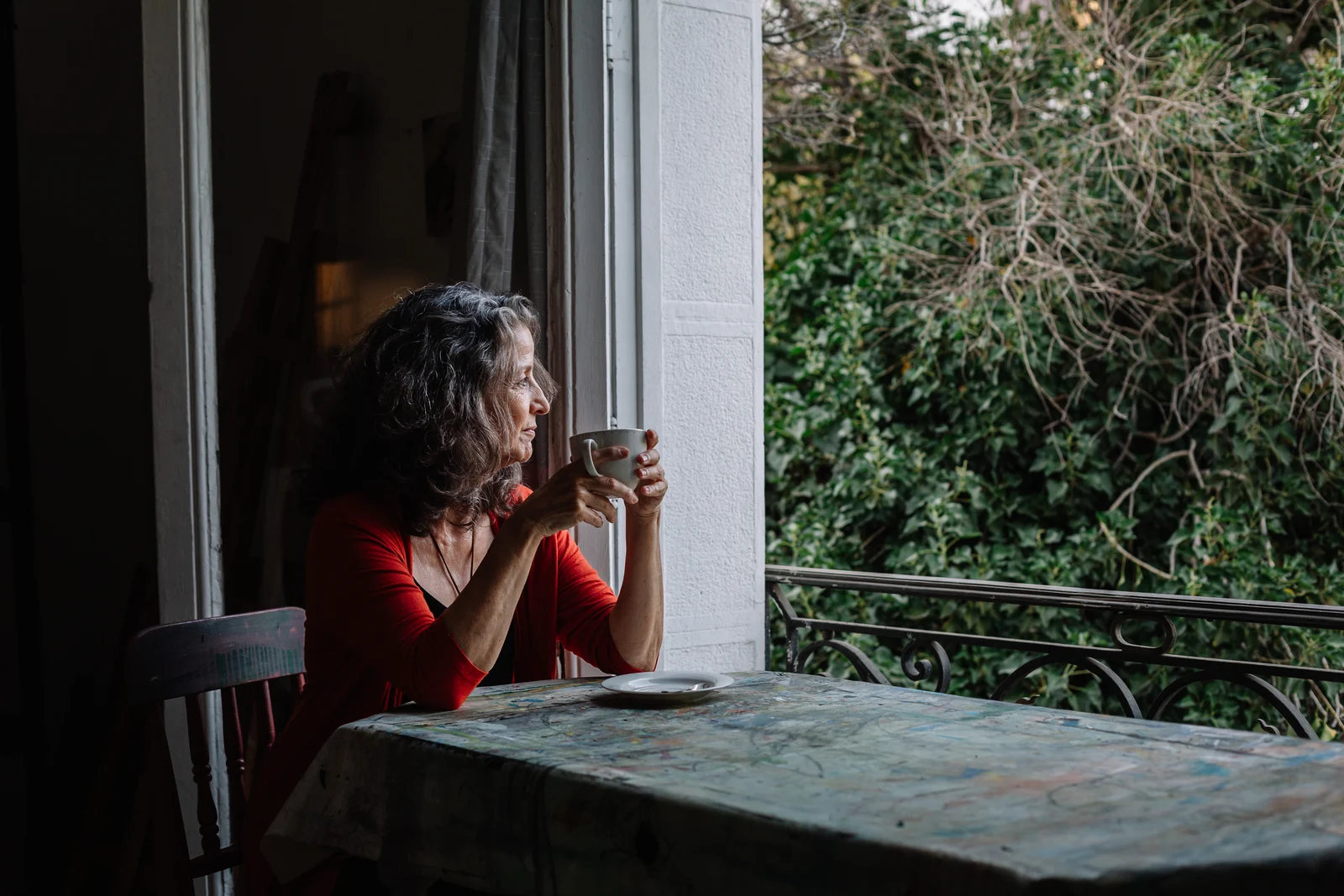 Victoria Valjalo drinking tea beside an open studio window and climbing plants.