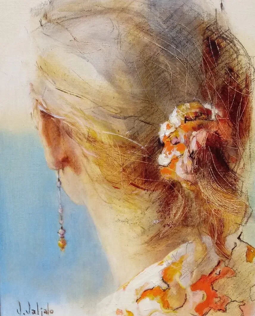 A close view of a woman’s brown bun, with an orange flower and warm colour at her shoulder.